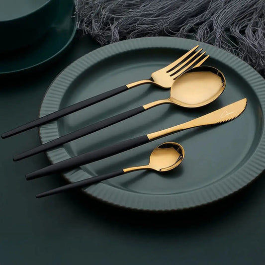 omplete black and gold cutlery set for four, including forks, knives, spoons, and teaspoons laid out in an elegant arrangement.