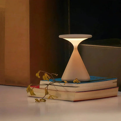 GlowSphere hourglass lamp set up in a cozy corner, creating a warm and inviting atmosphere for reading or relaxing.

